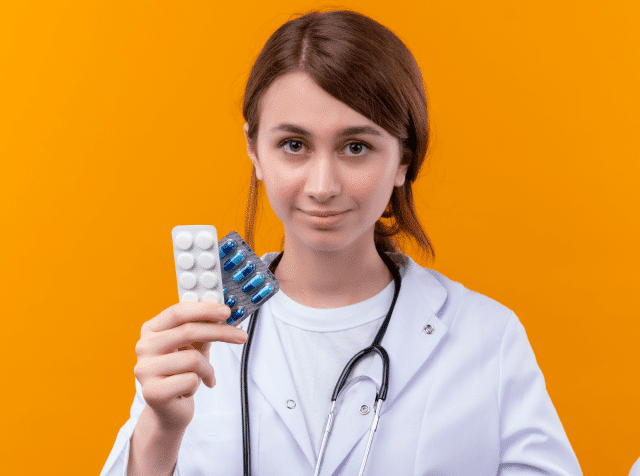 confident-young-female-doctor-wearing-medical-robe-stethoscope-holding-medical-drugs-showing-empty-hand-isolated-orange-space 1-min